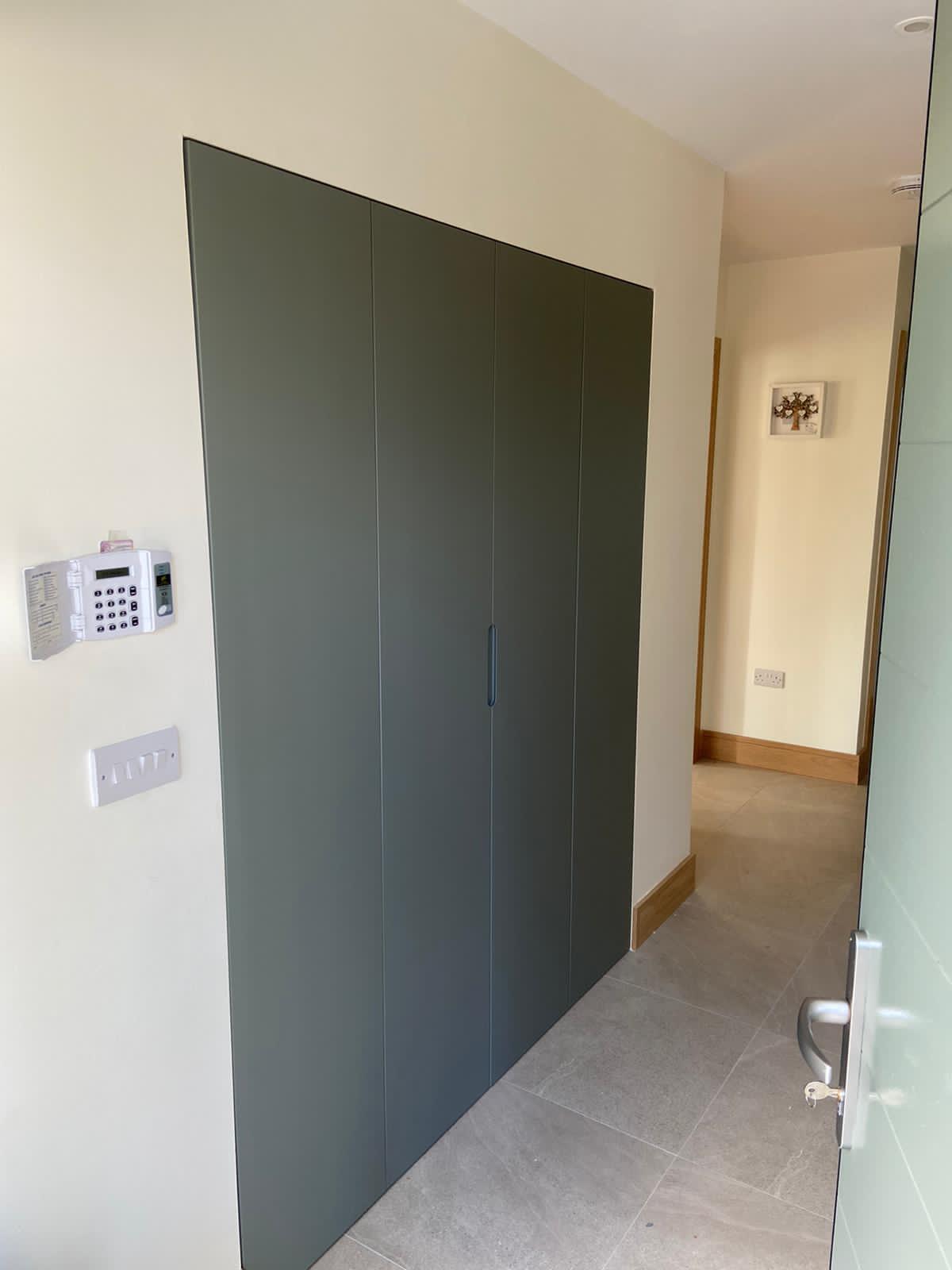 Sage entry area fitted wardrobe with clean full-height doors.