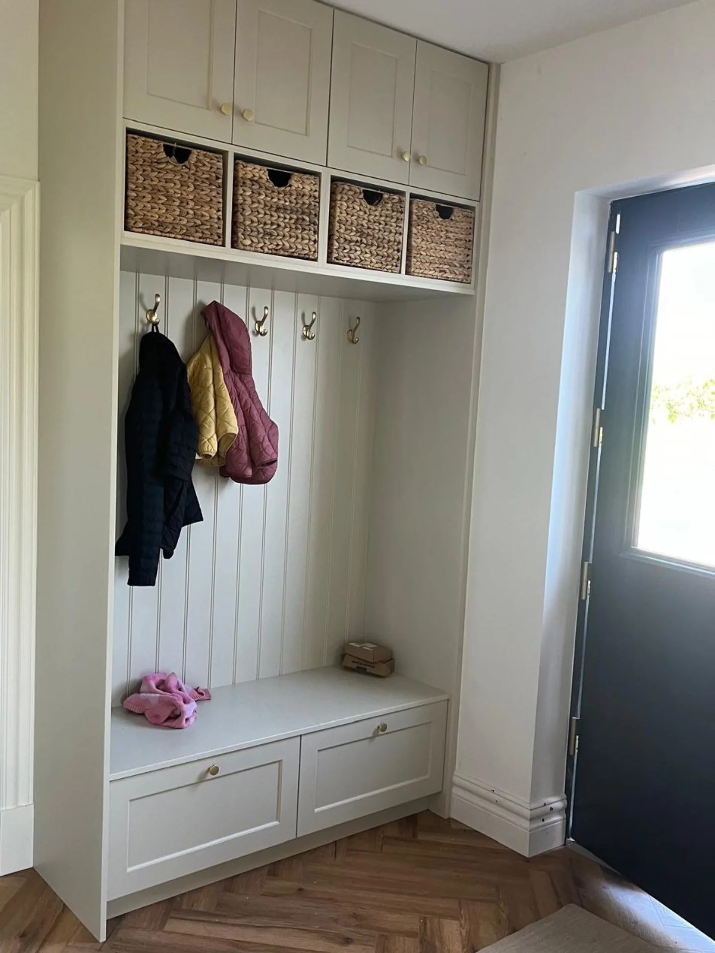 Entryway fitted storage with bench seating, shelving and cabinetry.