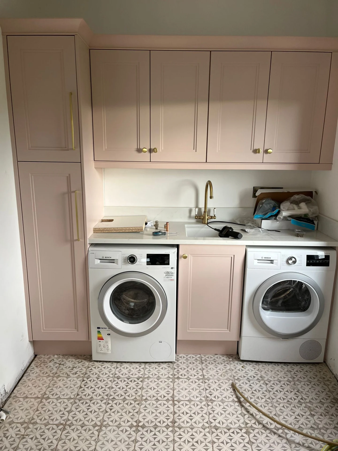 Front view of pink utility laundry cabinetry with made-to-measure storage.