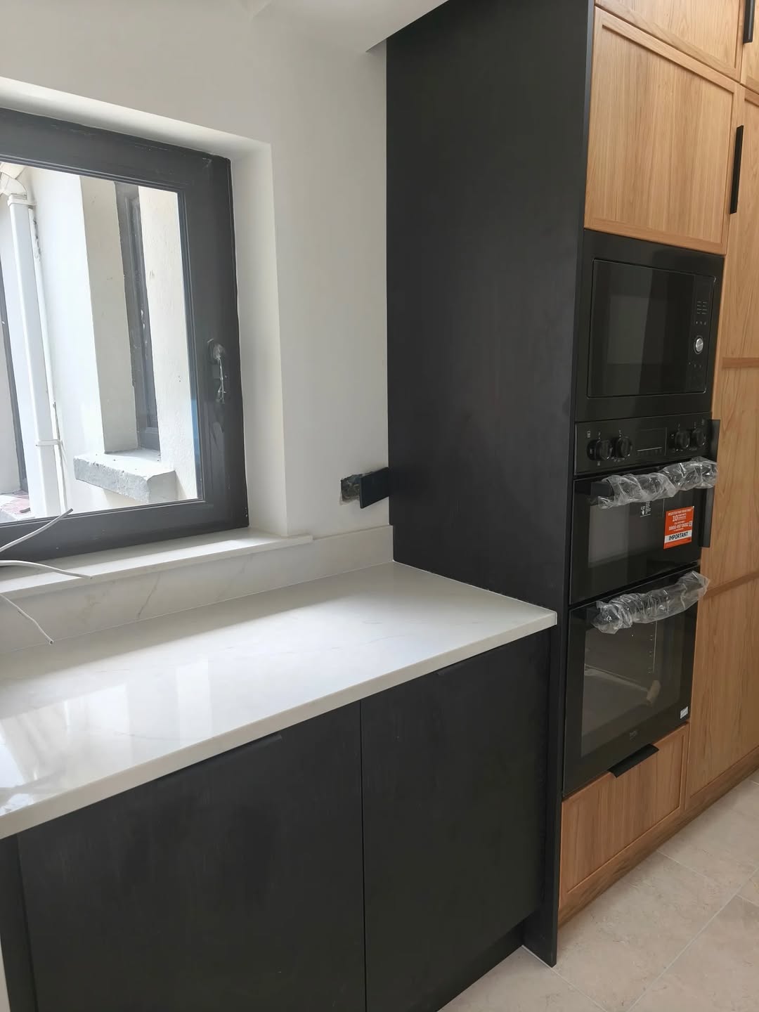 Close view of black and oak fitted kitchen cabinetry with integrated appliances.