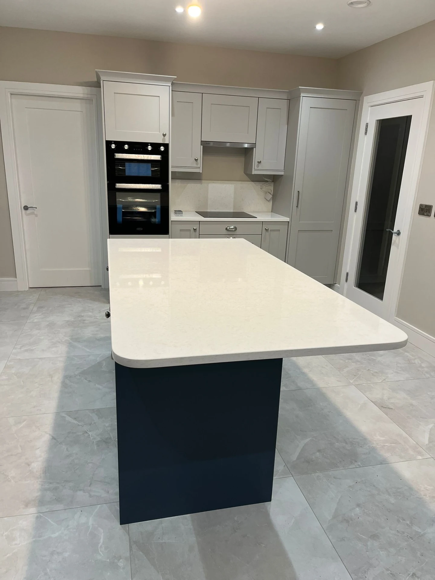 Grey shaker kitchen with island, fitted drawers and bright worktop run.