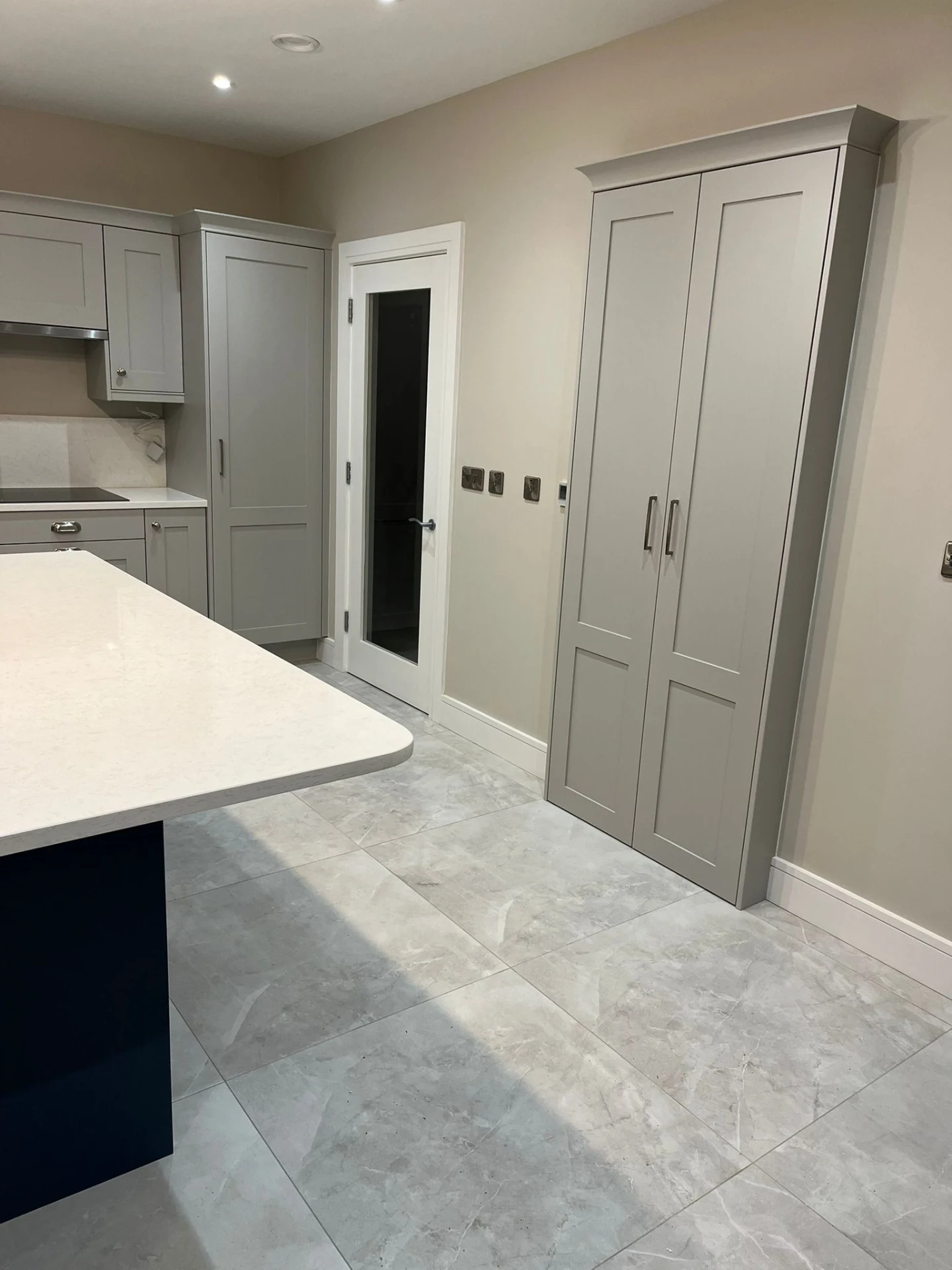 Grey shaker kitchen with tall fitted storage and integrated cabinetry.