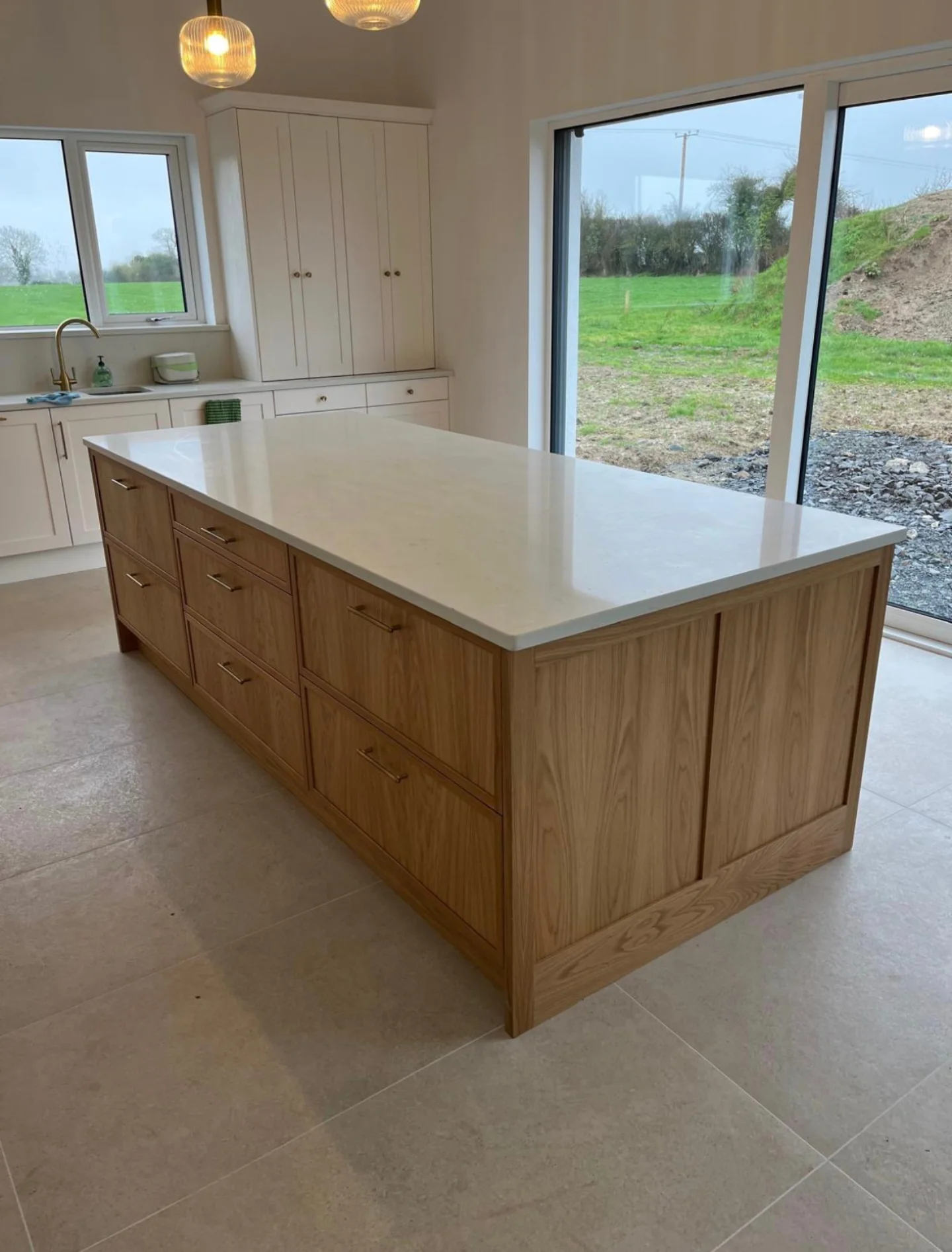 Oak kitchen island and fitted cabinetry in a bright room with large windows.