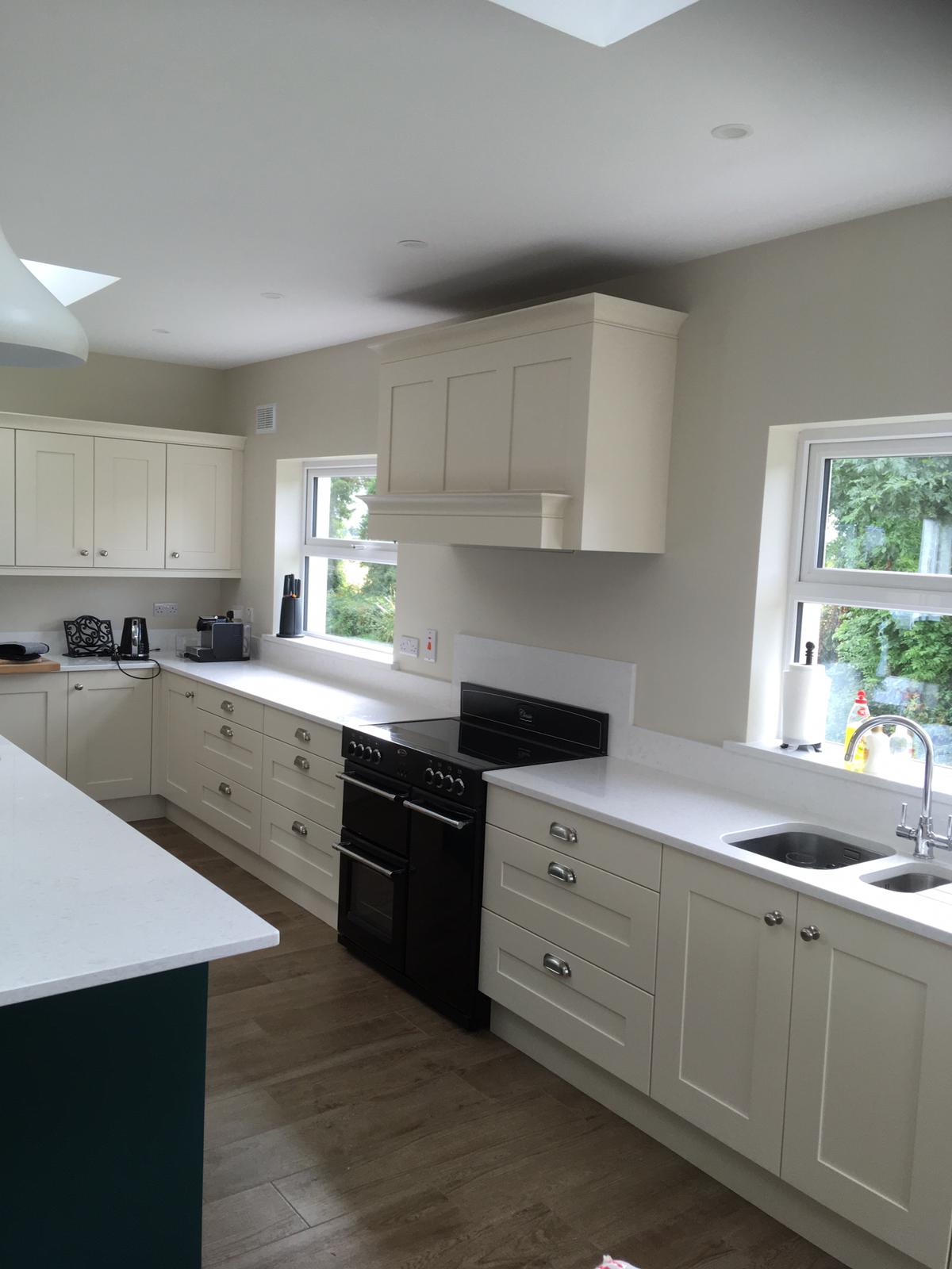 White fitted kitchen with teal island edge, range cooker and bright cabinetry detail.