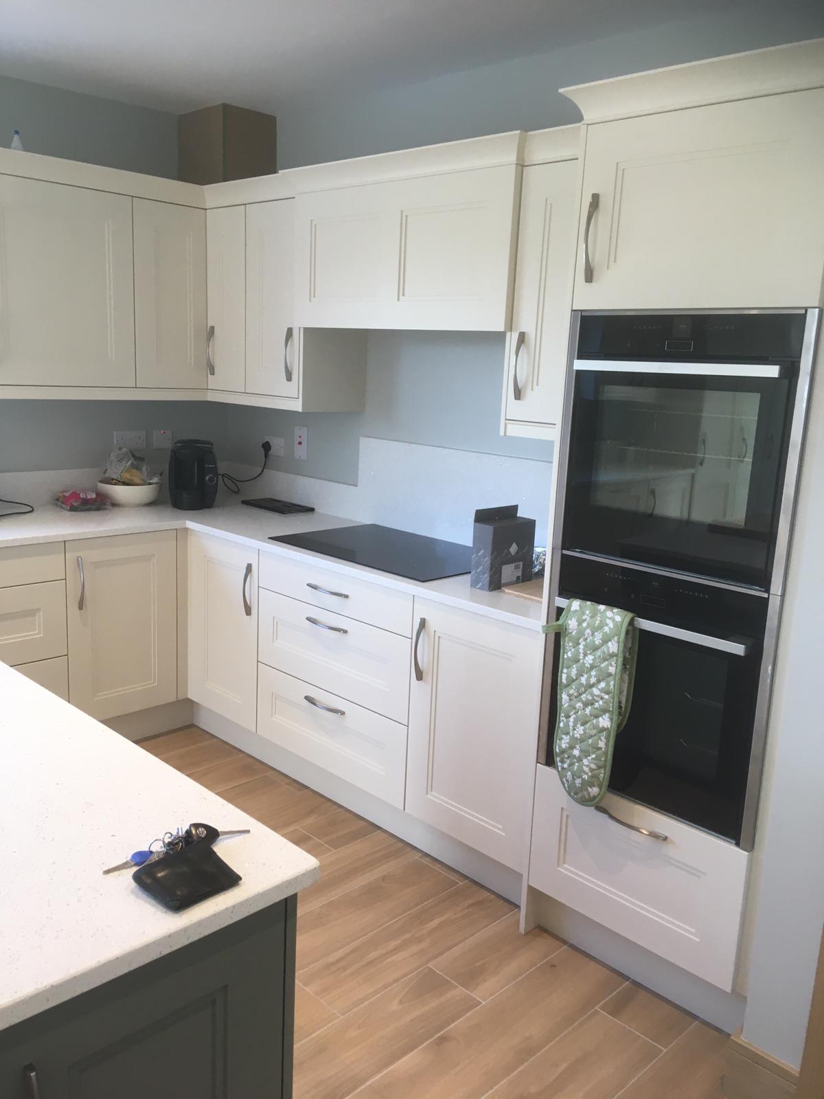White fitted kitchen with black ovens, appliance wall and custom cabinetry.