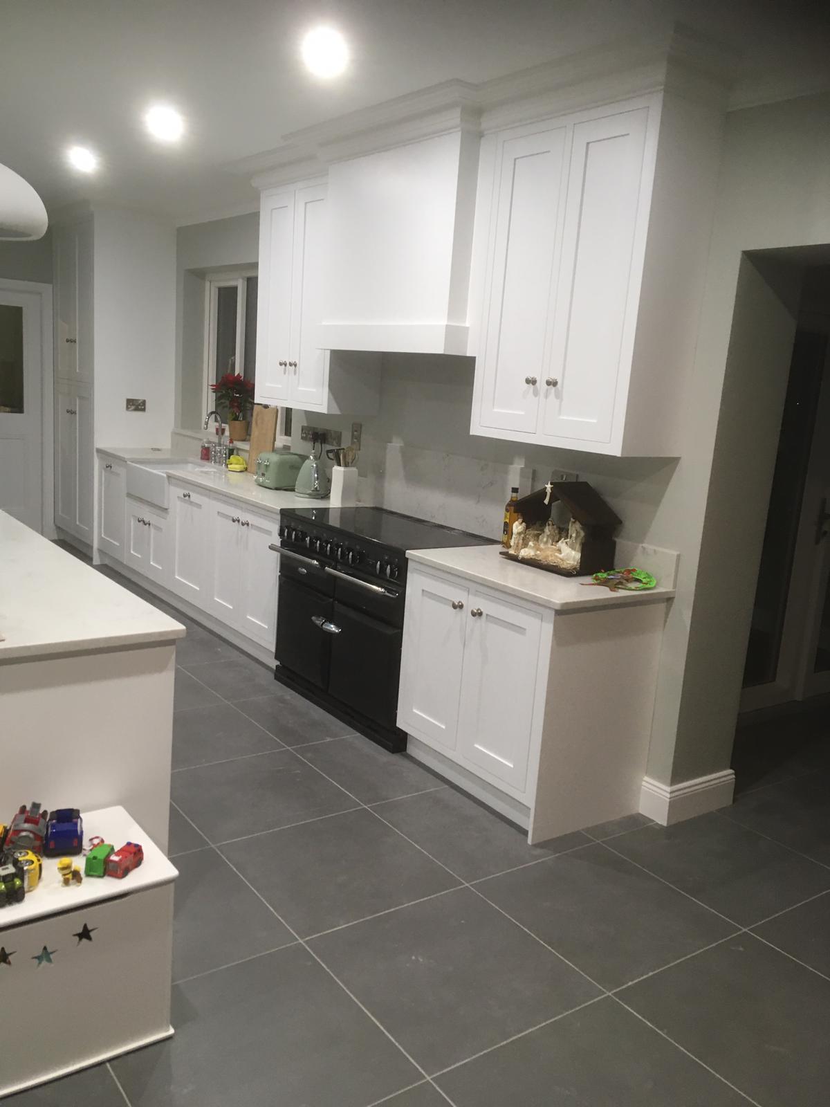 Classic white fitted kitchen with range cooker, custom extractor canopy and stone worktops.