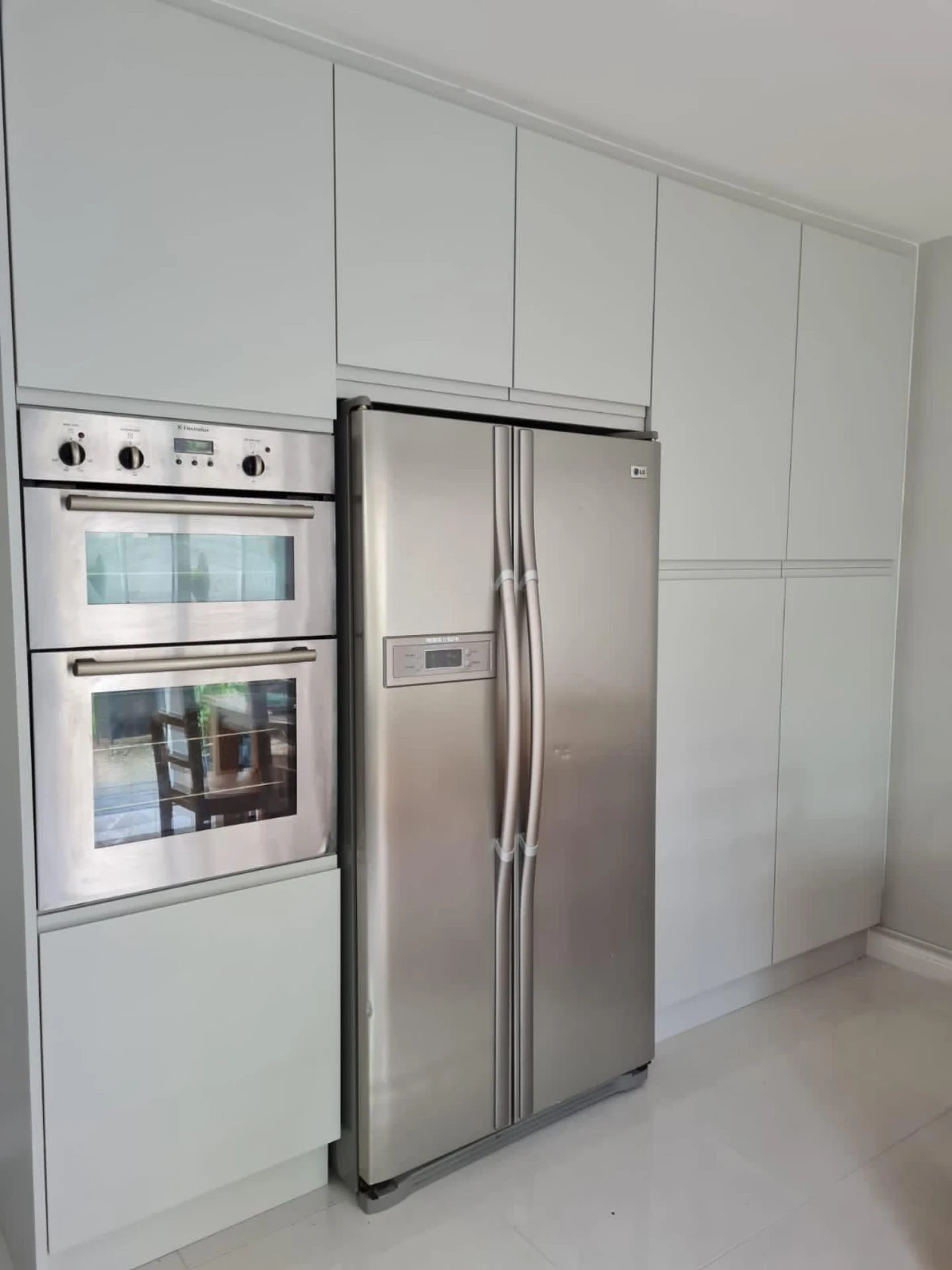 Minimal white fitted kitchen with integrated fridge and oven wall cabinetry.