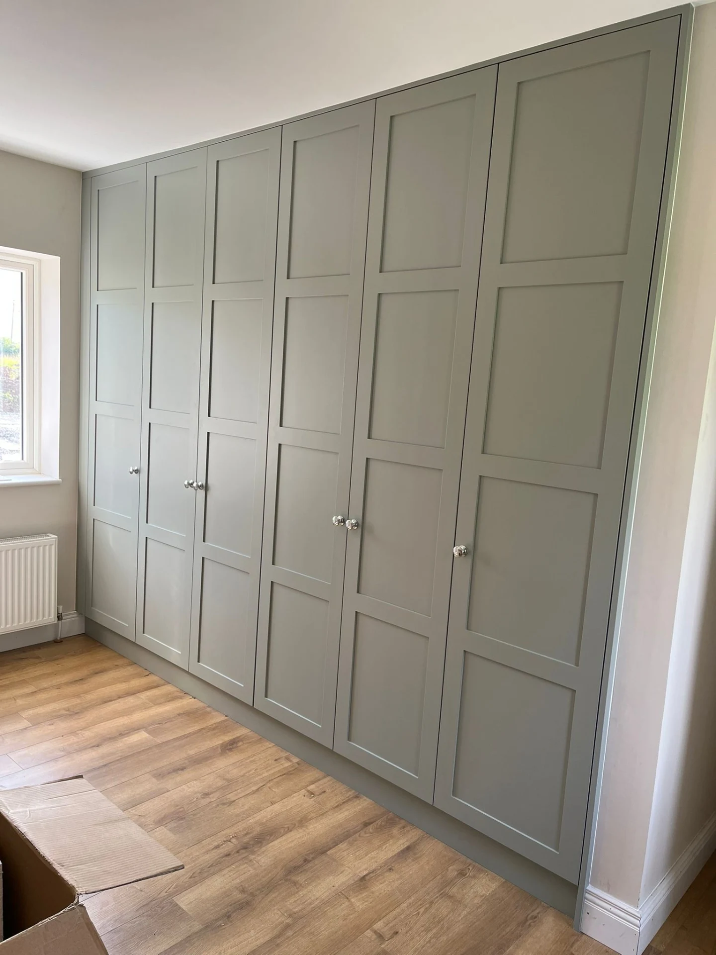 Sage fitted bedroom wardrobes with full-height doors and integrated storage.